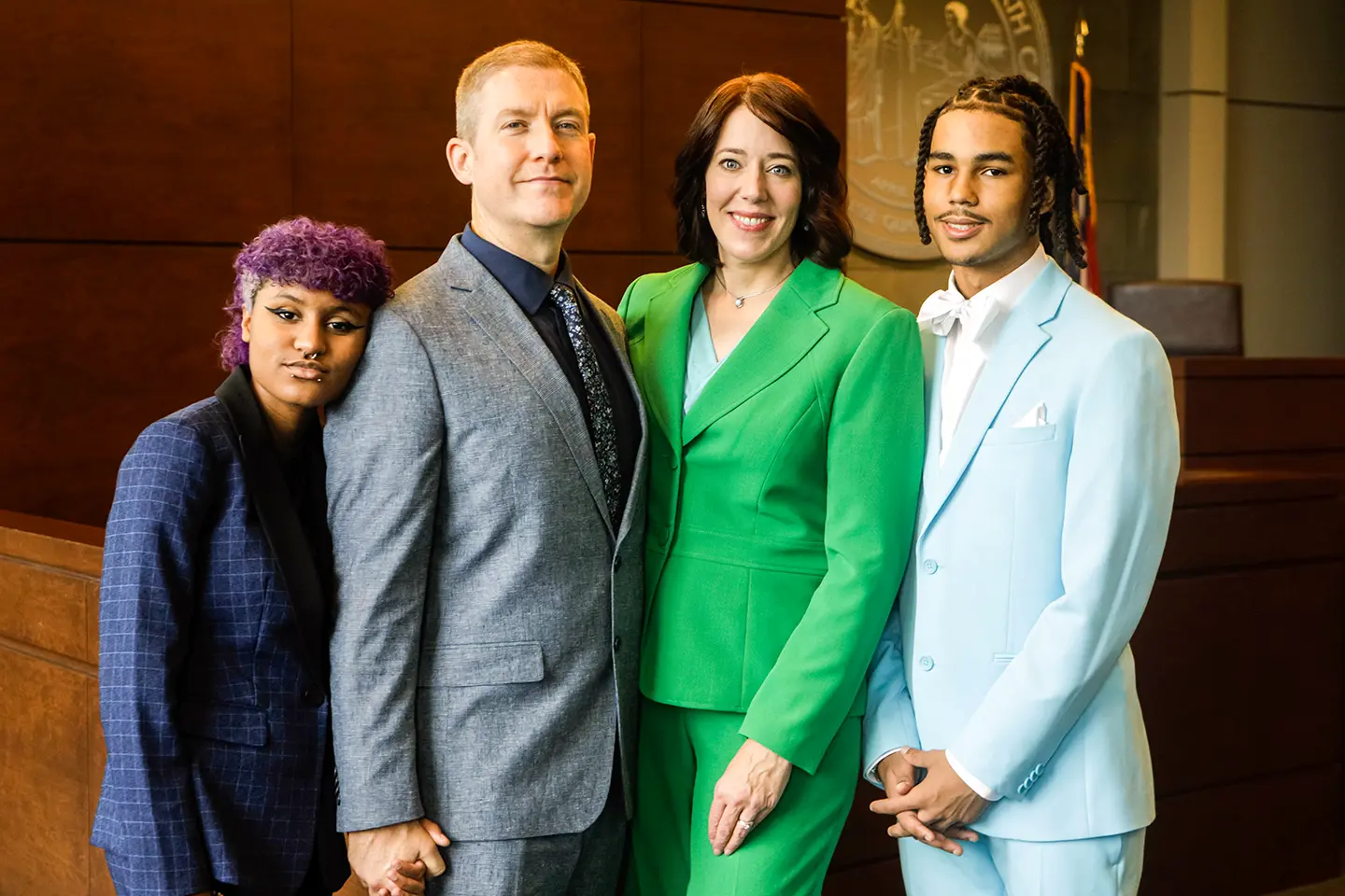 Kendra Montgomery-Blinn in a green suit standing in the court room alongside her family.